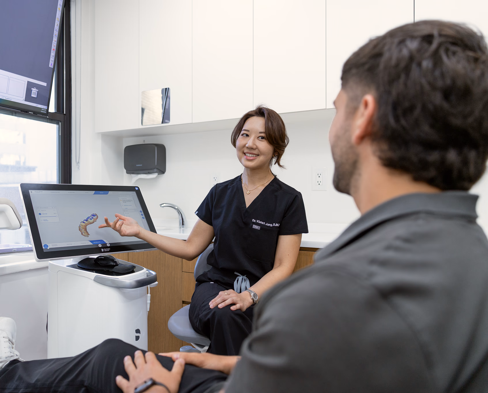 Dr. Violet Jang walking a patient through their digital treatment plan on an intraoral scanner display